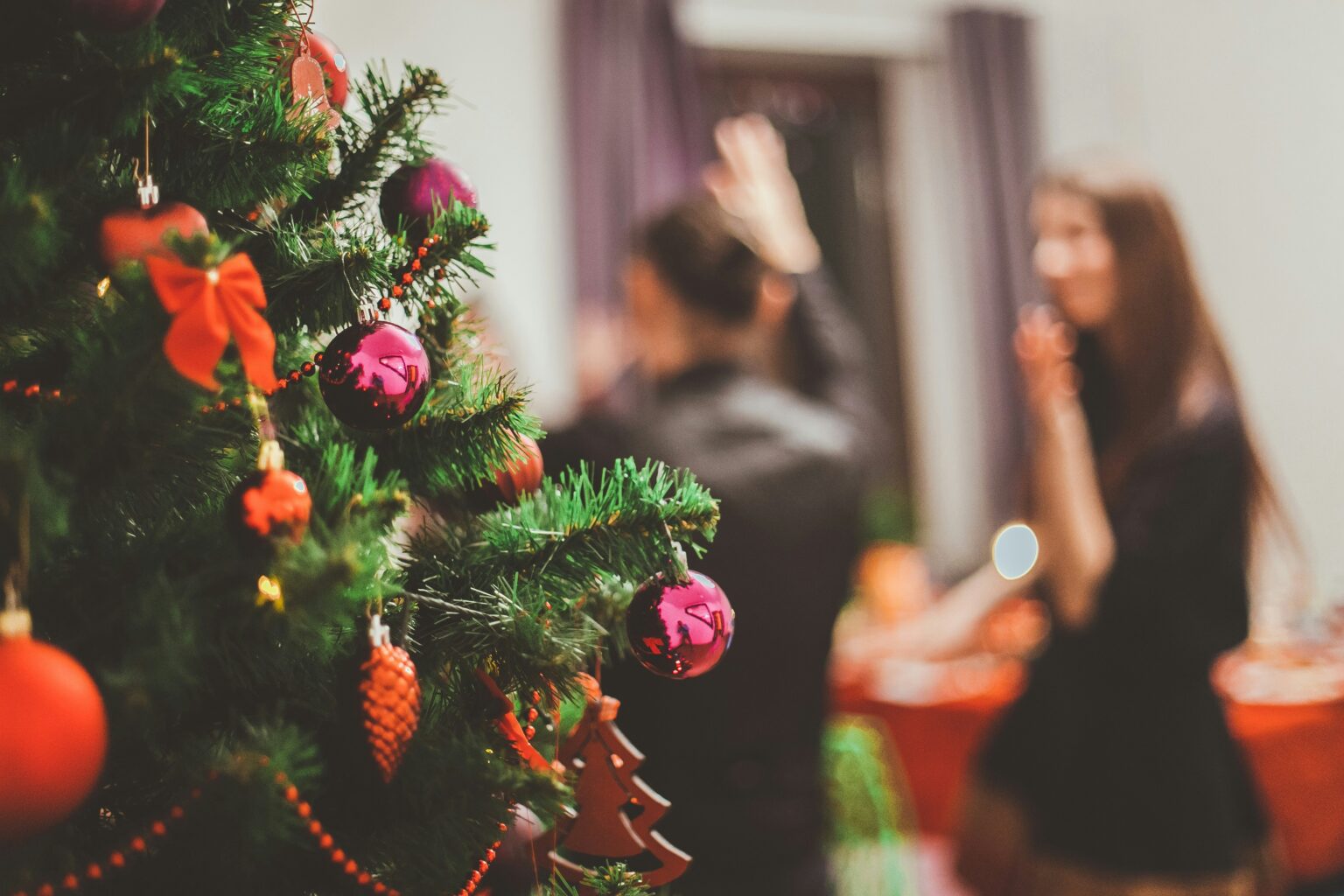 Close-up shot of a Christmas tree with party guests blurred in the background