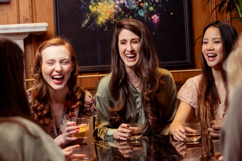 Group of woman sitting at a table drinking and laughing