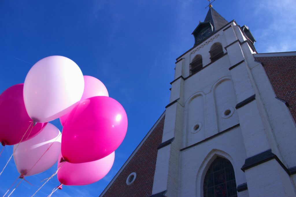 Shot looking up, with balloons and and a church's front in the frame
